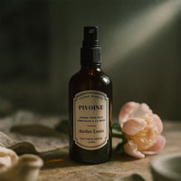 Bottle of Atelier Louis Pivoine crème végétale with a pink flower in the background